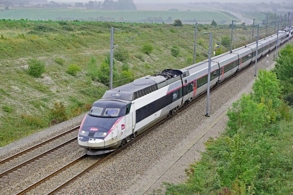 Un TGV de la SNCF roulant sur une voie ferrée à travers une campagne verdoyante.
